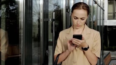 Yetişkin Kafkasyalı Kendine güvenen Genç İş Kadını Modern Ofis Binası 'nın dışında telefonla konuşuyor.