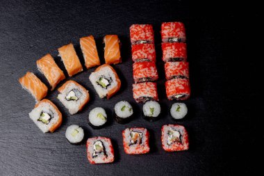 Siyah arkaplanda suşi rulosu. Philadelphia balık, Japon somonu. Lezzetli suşi, pirinç, salatalık, geleneksel wasabi taze, sağlıklı, çiğ gurme..