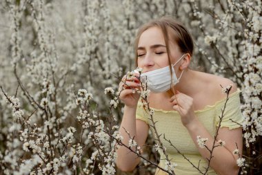 Genç kız sümkürme ve çiçek açan ağacın önünde mendile hapşırma. İnsanları etkileyen mevsimsel alerjik maddeler. Güzel bayanın rhinitis 'i var..
