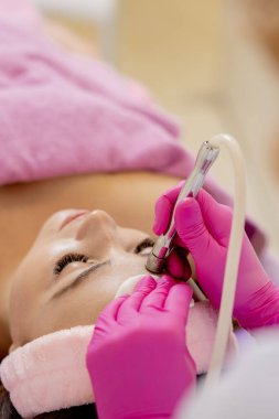 Kozmetik uzmanı, güzellik salonundaki güzel, genç bir kadının yüz derisinin mikro cilt bakımını yapıyor. Kozmetoloji ve profesyonel cilt bakımı.