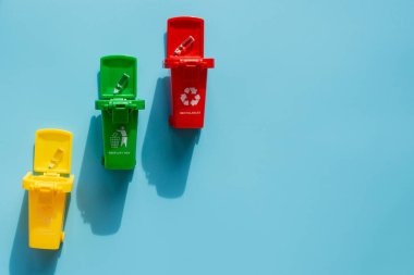 Sarı, yeşil ve kırmızı geri dönüşüm kutularında mavi arka planda geri dönüşüm sembolü var. Şehri düzenli tutar, geri dönüşüm sembolünü bırakır. Doğa koruma kavramı.