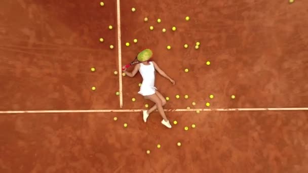 在室外艰苦的网球训练之后 带着很多球和球拍在网球场上放松的微笑女孩的画像 多莉开枪了顶部视图 — 图库视频影像