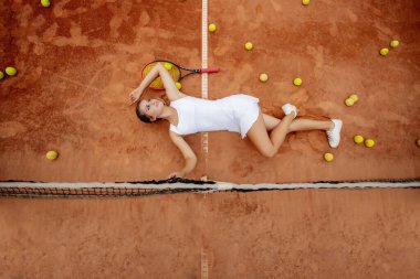 Tenis antrenmanından sonra dinleniyorum. Beyaz üniformalı, spor şapkalı, tenis kortunda uzanan genç ve güzel bir kız..