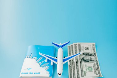 Pasaportunda yolcu uçağı modeli ve mavi arka planda dolar var. Seyahat kavramı, kopyalama alanı