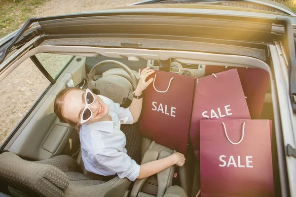 Una ragazza con le borse della spesa sta guidando un'auto, concetto di sconti e shopping, vista dall'alto — Foto Stock