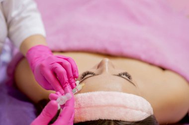 Kafkasyalı genç bir kadının portresi. Alnına botoks yapılıyor. Güzel bir kadın yüzüne botoks yaptırıyor. Kozmetoloji cilt bakımı