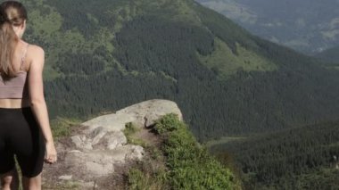 Güçlü kadın yürüyüşçü kollarını açmış dağın yamacında dikiliyor.