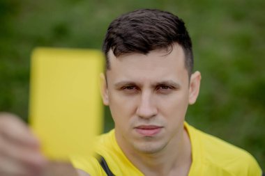 Hakem, hoşnutsuz bir futbol oyuncusu ya da futbolcuya kırmızı kart gösteriyor. Spor anlayışı, kural ihlali, tartışmalı konular, engellerin aşılması