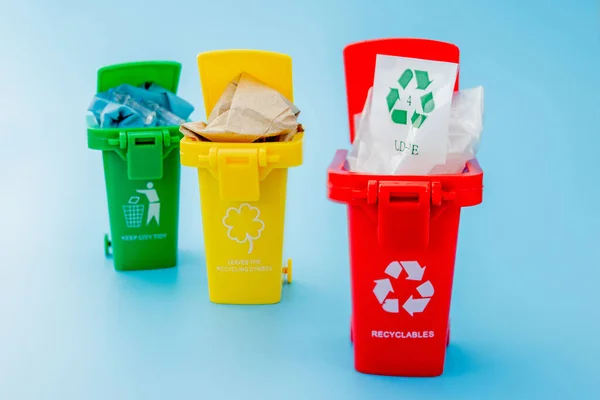 青色の背景にリサイクルシンボルを持つ黄色 赤のごみ箱 街を整頓し リサイクルのシンボルを残します 自然保護の概念 — ストック写真