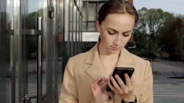 Yetişkin Kafkasyalı Kendine güvenen Genç İş Kadını Modern Ofis Binası 'nın dışında telefonla konuşuyor.