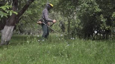 Elinde çim biçme makinesiyle evin önünde çim biçen bir işçi. Bir adamın ellerinde budayıcı. Bahçıvan çimleri biçiyor. Yaşam biçimi