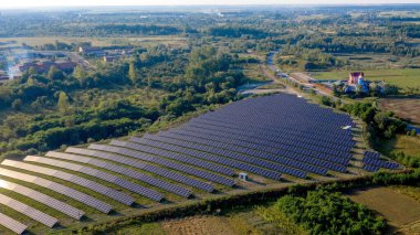 Güneşli bir günde, Yeşil Alan 'daki güneş enerjisi istasyonu. Hava görüntüsü. Güneş Panelleri Güç Üretimi Alanında Bir Satırda Duruyor. İnsansız hava aracı Güneş Çiftliği üzerinde uçuyor. Yenilenebilir yeşil enerji. Alternatif enerji kaynakları