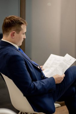 Belgelerle çalışan genç işadamı dosyalara bakıyor, büro masasında oturuyor..