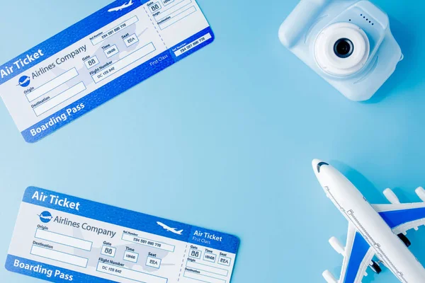 Flight tickets. camera, model of airplane and globe on blue background. Summer or vacation concept. Copy space.