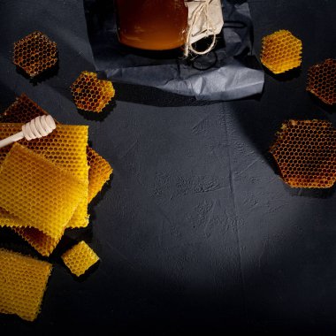 Kavanozda bal ve bal peteği. Siyah tahta bir arka planda. Metin için boş alan. Üst görünüm