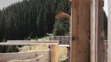 Sabahları dağ manzaralı ahşap bir kulübeden bir kadın çıkıyor.