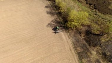 Havadan bakıldığında büyük bir traktör kuru bir alan oluşturuyor. Yukarıdan aşağıya traktör, toprağı işliyor ve kuru bir tarla ekiyor. Hava traktörü, tarla ekimi için çayırları kesiyor.