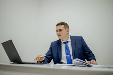 Belgelerle çalışan genç işadamı dosyalara bakıyor, büro masasında oturuyor..