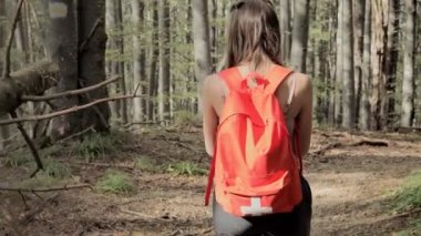 Ormanın ortasında duran bir kadın, akıllı telefonda navigasyon uygulaması kullanıyor, haritanın yardımıyla rotayı takip ediyor, cihaz ekranına bakıyor, ormanda kendini kaybederken akıllı telefon navigasyonunu kullanıyor..