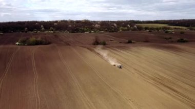 Havadan bakıldığında büyük bir traktör kuru bir alan oluşturuyor. Yukarıdan aşağıya traktör, toprağı işliyor ve kuru bir tarla ekiyor. Hava traktörü, tarla ekimi için çayırları kesiyor.