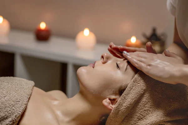 Relaxing massage. Woman receiving head massage at spa salon, side view