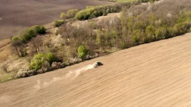 Havadan bakıldığında büyük bir traktör kuru bir alan oluşturuyor. Yukarıdan aşağıya traktör, toprağı işliyor ve kuru bir tarla ekiyor. Hava traktörü, tarla ekimi için çayırları kesiyor.