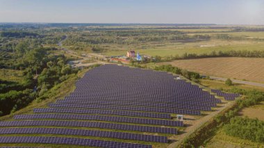 Güneşli bir günde, Yeşil Alan 'daki güneş enerjisi istasyonu. Hava görüntüsü. Güneş Panelleri Güç Üretimi Alanında Bir Satırda Duruyor. İnsansız hava aracı Güneş Çiftliği üzerinde uçuyor. Yenilenebilir yeşil enerji. Alternatif enerji kaynakları
