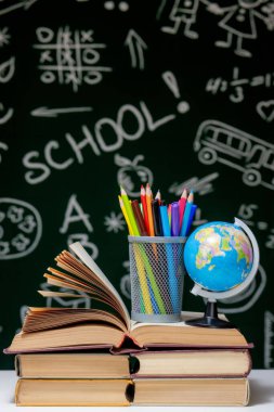 Kitap, kalem ve küre ile okul arka planına yeşil karatahta arka planında beyaz masa üzerinde