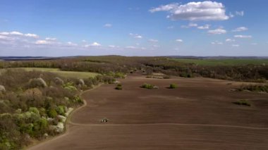 Havadan bakıldığında büyük bir traktör kuru bir alan oluşturuyor. Yukarıdan aşağıya traktör, toprağı işliyor ve kuru bir tarla ekiyor. Hava traktörü, tarla ekimi için çayırları kesiyor