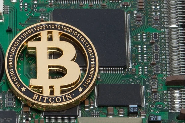 Close-up of gold bit coin, computer circuit board with bitcoin processor and microchips. Electronic currency, internet finance rypto currency. Bitcoin mining.