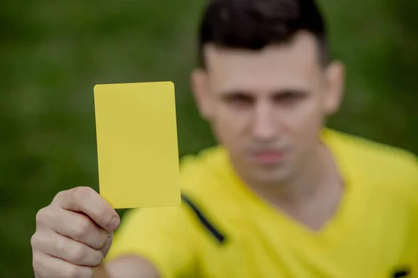 Soccer referee to point out a yellow card to a player in the soccer stadium.