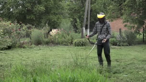 彼の手にガスの粉を持つ労働者は 家の前に草を刈る 男の手にトリマー 草を切る庭師 ライフスタイル — ストック動画