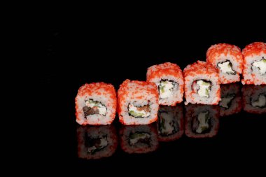 Philadelphia rulosu somon, peynir ve salatalık ile siyah arka planda yansımalı. Suşi Philadelphia.