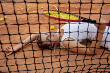 Tenis antrenmanından sonra dinleniyorum. Beyaz üniformalı, spor şapkalı, tenis kortunda uzanan genç ve güzel bir kız..