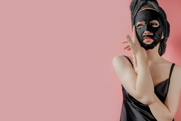 Jonge Vrouw Toe Passen Zwarte Cosmetische Stof Gezichtsmasker Roze Achtergrond — Stockfoto