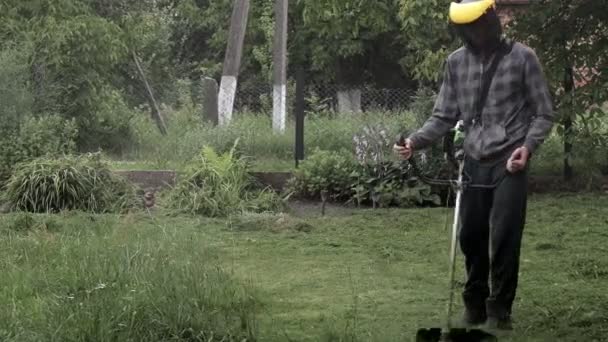 彼の手にガスの粉を持つ労働者は 家の前に草を刈る 男の手にトリマー 草を切る庭師 ライフスタイル — ストック動画