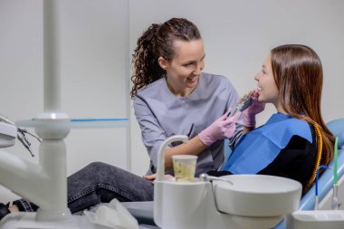 Diş hekimi güzel bir kadın için diş implantı için doğru rengi seçmeye çalışıyor.
