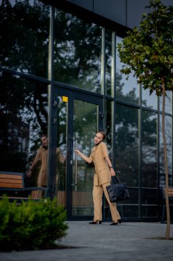 Genç bayan yönetici ofis binasının önünde cep telefonuyla konuşuyor. Beyaz iş kadını, bir şirket binasına karşı dururken telefonla konuşuyor.