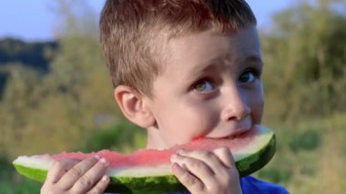 Yazın karpuz yiyen bir çocuk. Küçük çocuk tatilde meyve yiyor..