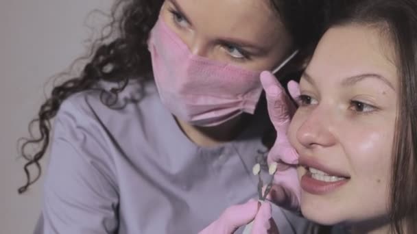 歯医者は美しい女性のためのインプラントのための右の色を選択しようとしています — ストック動画