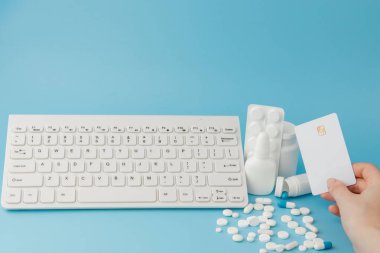 İlaç ve klavyeli alışveriş arabası oyuncağı. Haplar, su toplayan paketler, tıbbi şişeler, termometre, mavi arka planda koruyucu maske. - Evet. Sağlık ve internet alışverişi. Metniniz için en üstteki görünüm.