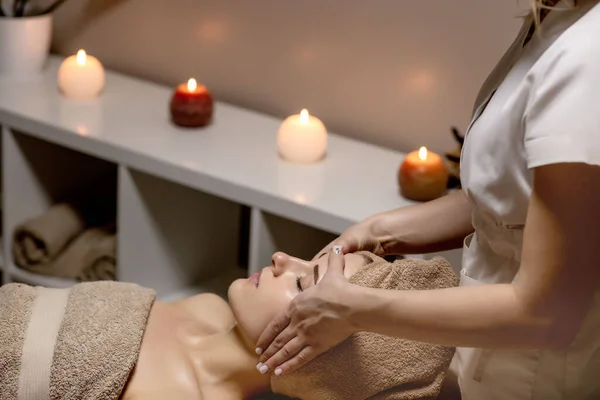 Relaxing massage. Woman receiving head massage at spa salon, side view.