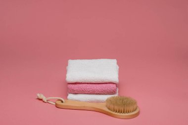 Anti-selülit masajı için vücut fırçası ve pembe arka planda yumuşak havlularla cilt tedavisi. Tasarımı kopyalama alanı ile düzenleyin. Spa konsepti