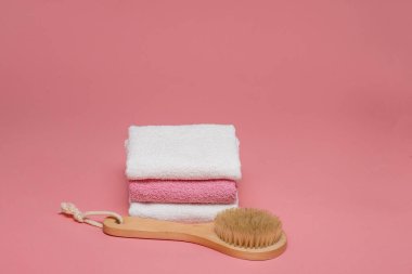 Anti-selülit masajı için vücut fırçası ve pembe arka planda yumuşak havlularla cilt tedavisi. Tasarımı kopyalama alanı ile düzenleyin. Spa konsepti