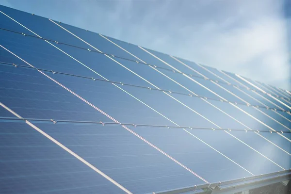 Solar Power Station in Green Field on Sunny day. Aerial view. Solar Panels Stands in a Row in Field for Power Production. Drone fly over Solar Farm. Renewable green energy. Alternative energy sources