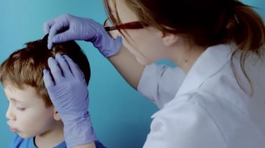 Eldivenli çocuk doktoru küçük bir çocuktaki bit ve bitleri kontrol edecek. Anaokulunda pediküloz, kafa ve saçın önleyici muayenesi.