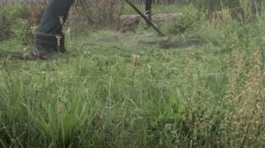Elektrikli çim biçme makinesiyle çim biçen bir işçi. Bahçıvanlık malzemeleri ve ekipmanlar. Çim biçme makinesiyle çim biçme işlemi