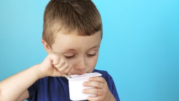Little Boy Eatiing Yogurt Blue Background — Stock Video