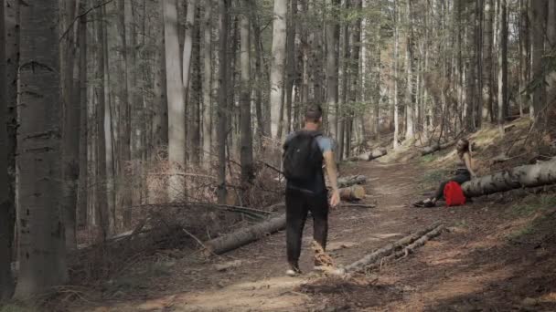 Мужчина помогает женщине, которая села отдохнуть в лесу, обрести свободу и концепцию активного образа жизни — стоковое видео
