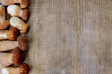 Tahta zeminin üzerinde mantar mantarı var. Autumn Cep Mantarları. Boletus Edulis 'i ahşap arka planda, ahşap kırsal masada yakalıyor. Lezzetli organik mantar pişiriyorum. Gurme yemekleri..